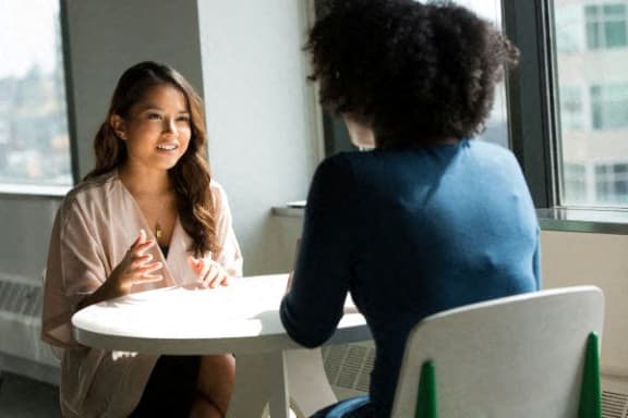 two women sitting at a table talking to each other