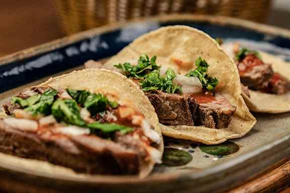 A plate of tacos with meat and garnish.