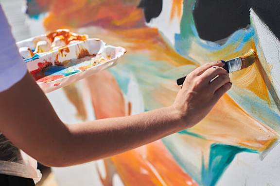 A person is painting a wall with a paintbrush.