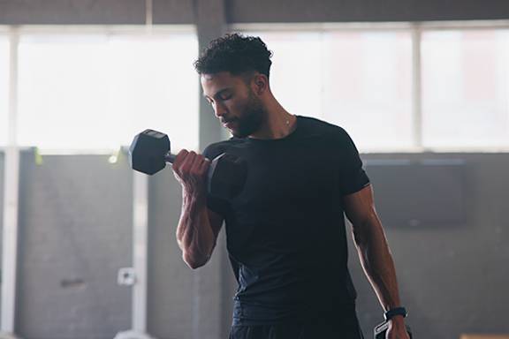 A man lifting a dumbbell in a gym.