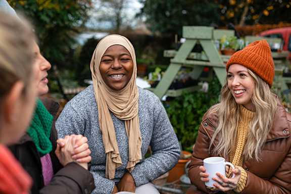 A group of people are sitting outside, enjoying a warm drink together.
