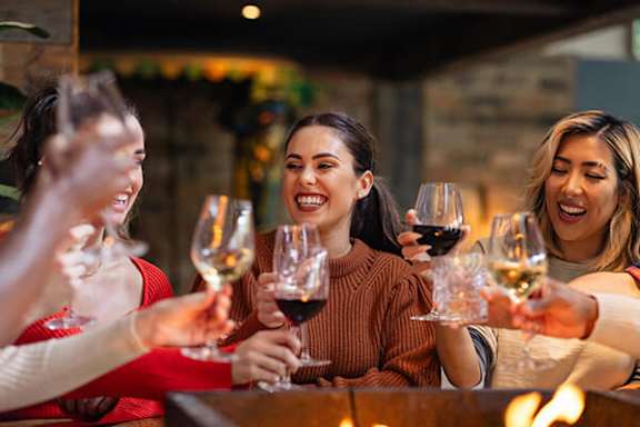 Four women toasting with wine glasses in a cozy setting.