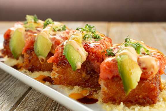 A white plate with a food item topped with sauce and garnished with green herbs.