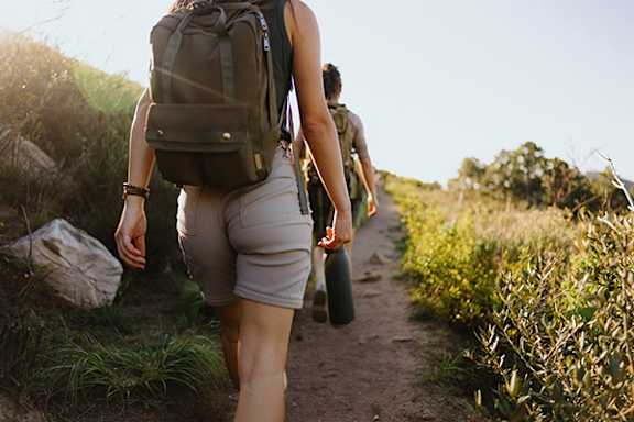 A woman with a backpack is walking on a trail.