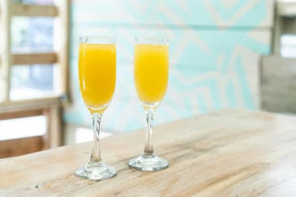 two glasses of orange juice on a wooden table