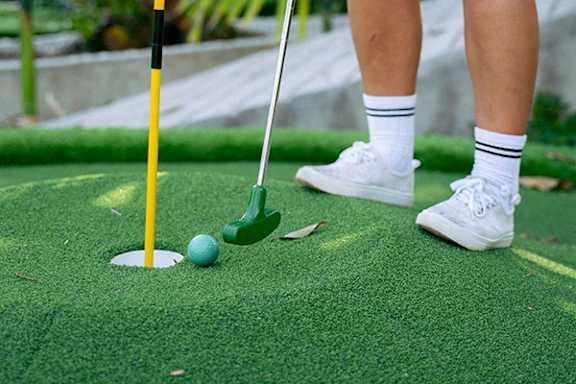 A person is about to hit a golf ball with a golf club.