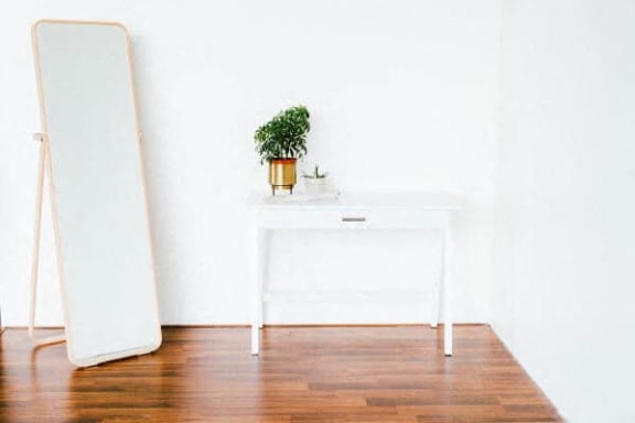 a white table with a mirror and a plant