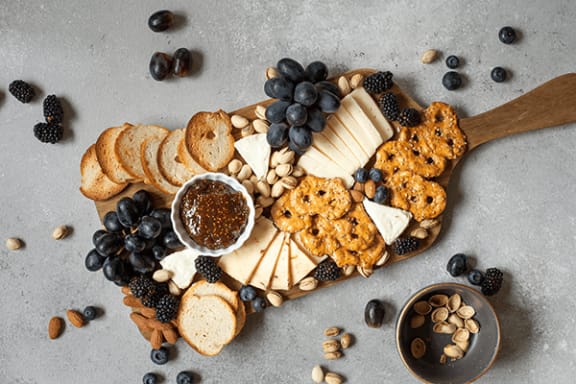 an overhead view of a cheese board with blackberries cheese and crackers