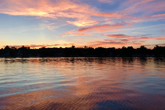 a sunset over a lake with trees in the background