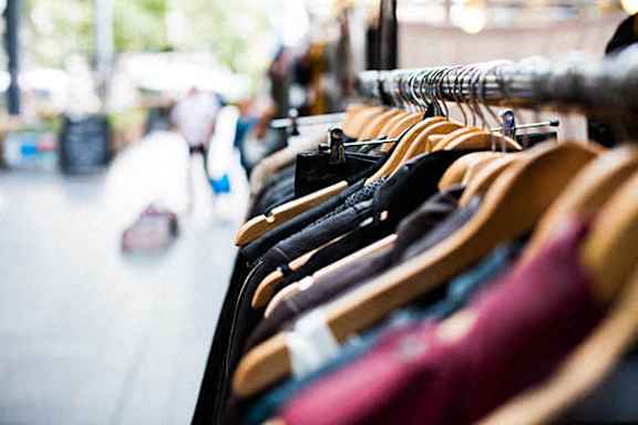 A row of clothes hanging on a rack in a store.