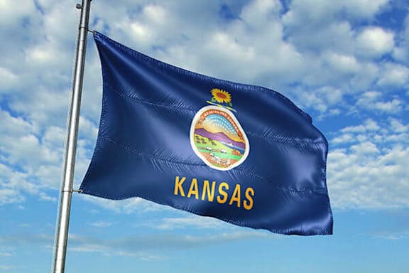 The flag of Kansas is waving in the sky.