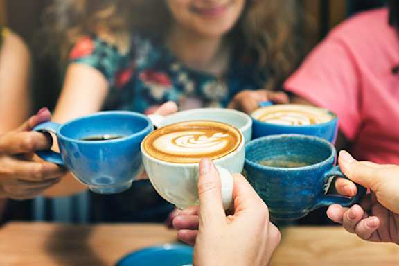 A group of people holding blue and white cups of coffee.