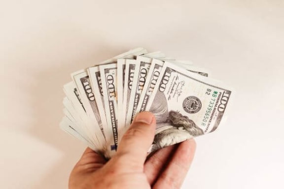 a hand holding a bunch of dollar bills