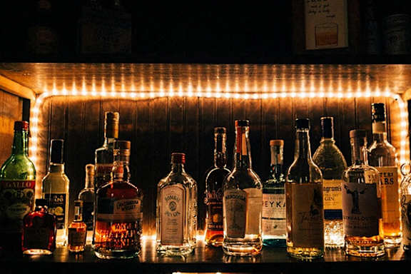 A bottle of Malibu is on a shelf with other bottles.