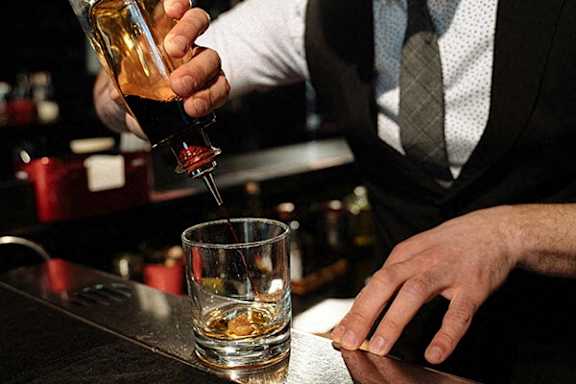 A bartender is pouring a drink into a glass.
