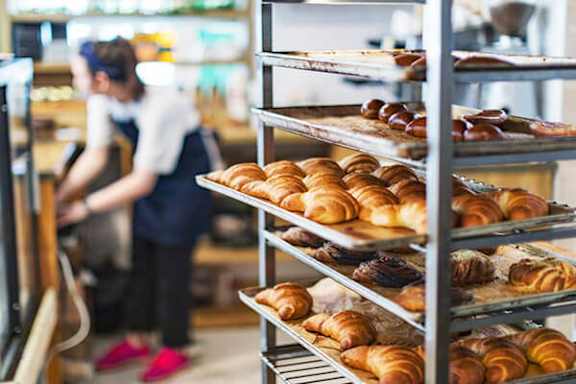 A baker is preparing croissants in a bakery.