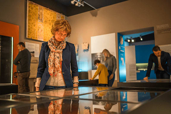 A woman in a scarf is looking at a display in a museum.