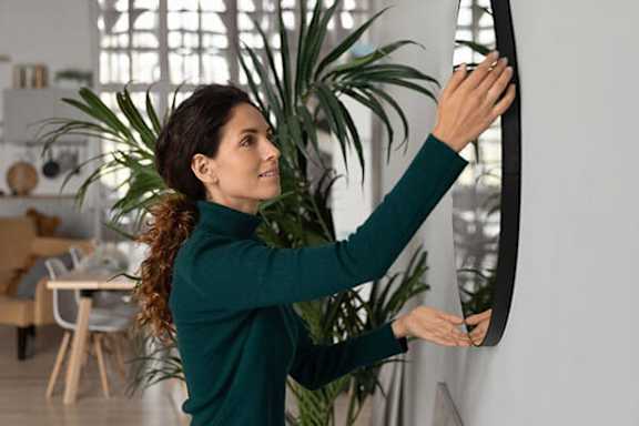 A woman in a green top is touching a white wall.
