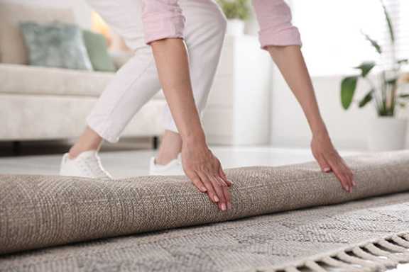 A person is rolling out a rug.