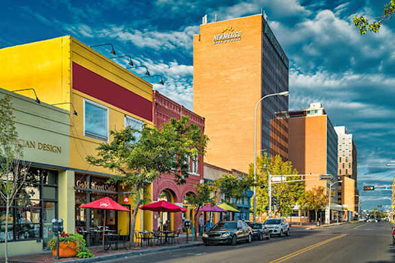 A street view of a city with a yellow building on the left and a tall building on the right.