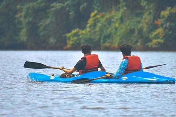 Two people kayaking on a blue kayak in a body of water.