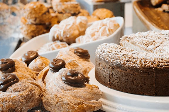 A variety of baked goods including pastries and a cake are displayed on a table.
