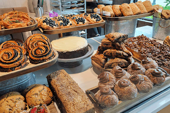 A display of various baked goods including cakes, pastries, and breads.