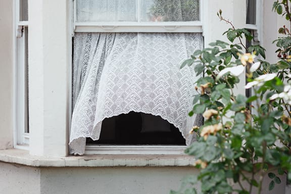an open window with a white lace curtain