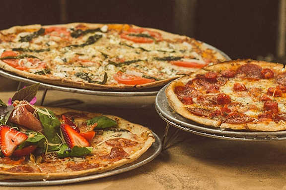 three pizzas sitting on top of a table
