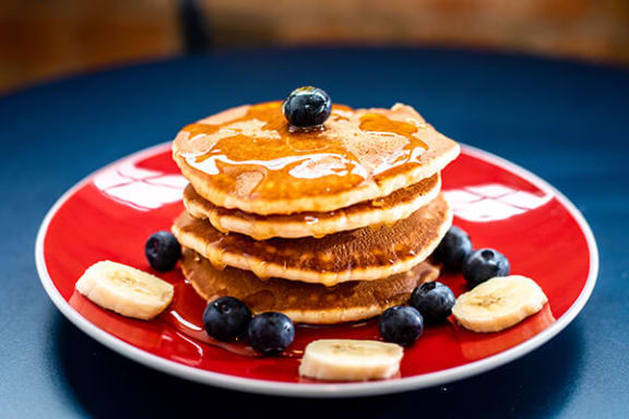 a red plate topped with a stack of pancakes and blueberries