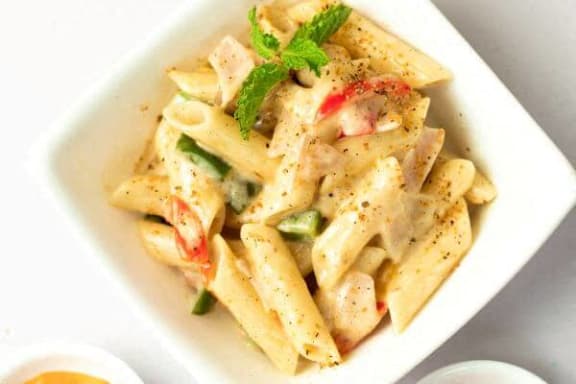 a white bowl of pasta with a garnish