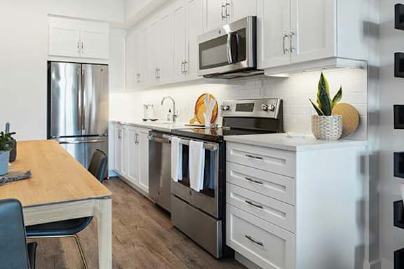A modern kitchen with white cabinets and stainless steel appliances.