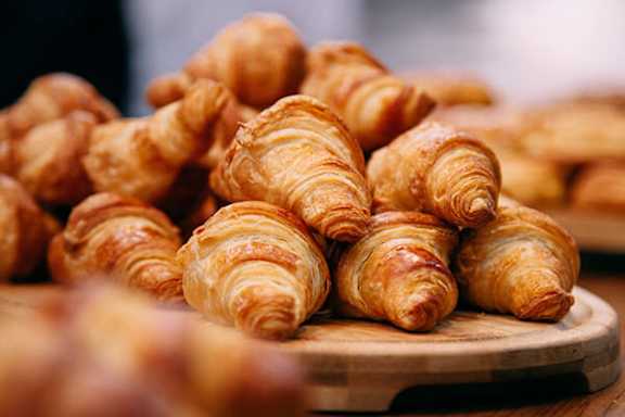 A pile of freshly baked croissants on a wooden board.