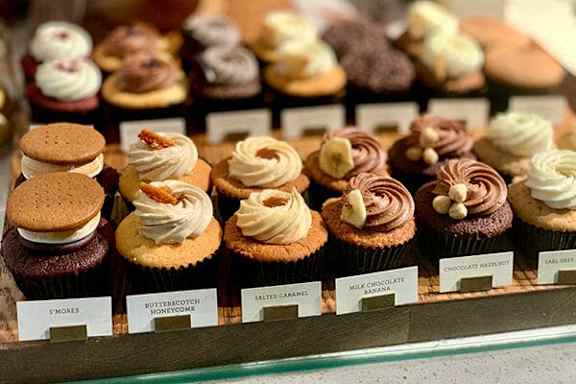 A display case filled with cupcakes and cookies.