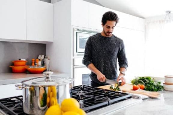 a man in a kitchen preparing food on a cutting board