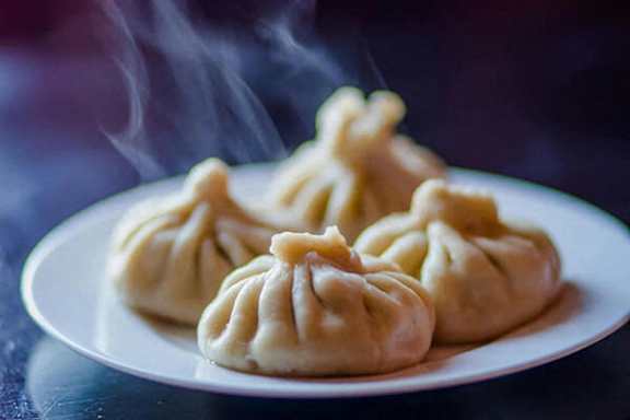 Steaming dumplings on a white plate.