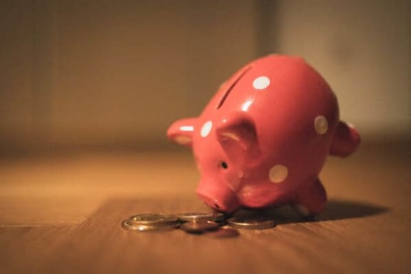 a pink piggy bank sitting on a table with coins