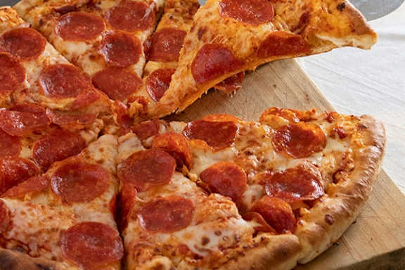 A pepperoni pizza with a slice being lifted.