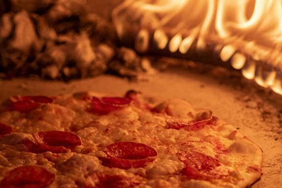a pepperoni pizza sitting in front of a pizza oven