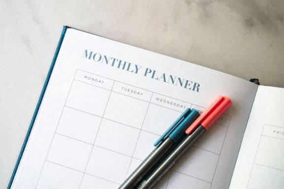 a monthly planner with two pens on top of it