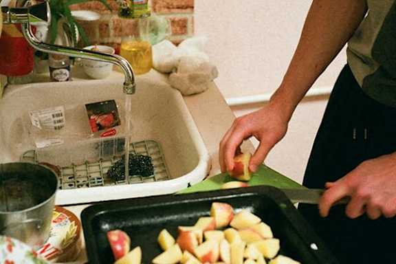A person is cutting an apple in a kitchen.