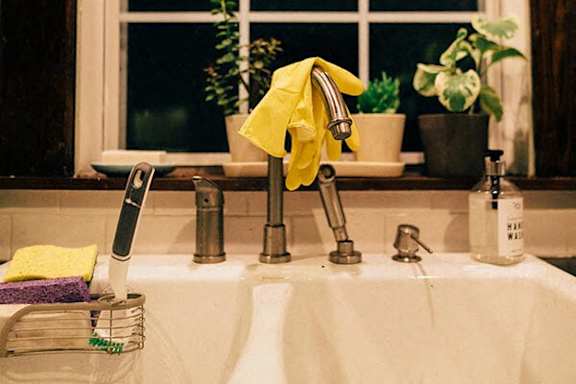 A yellow towel is hanging on a silver faucet.
