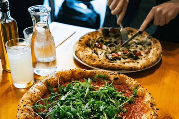 A person is cutting into a pizza with a variety of toppings.