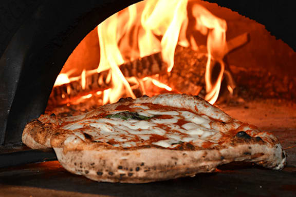 A pizza is being cooked in a wood-fired oven.