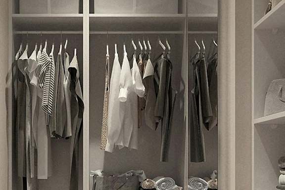 Clothes hanging on a rack in a closet.