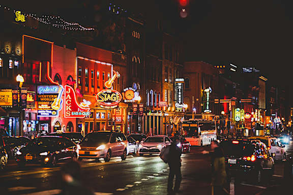 A busy street at night with cars and neon signs.