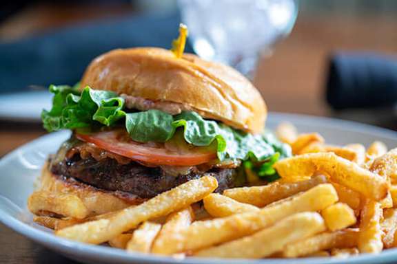 A burger with lettuce and tomato on a bun with fries.