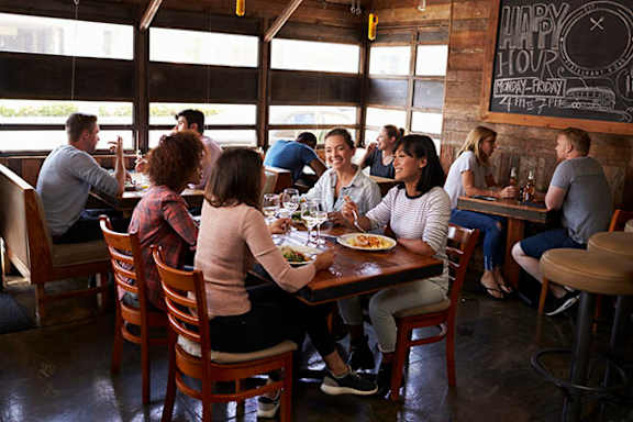 A group of people are sitting around a wooden table eating.