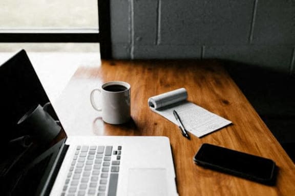 a laptop and a cup of coffee on a wooden desk
