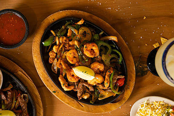 A wooden bowl filled with a seafood dish and garnished with lemon.